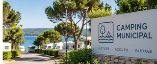 Allée d’un camping municipal avec mobil-homes et panneau d’accueil