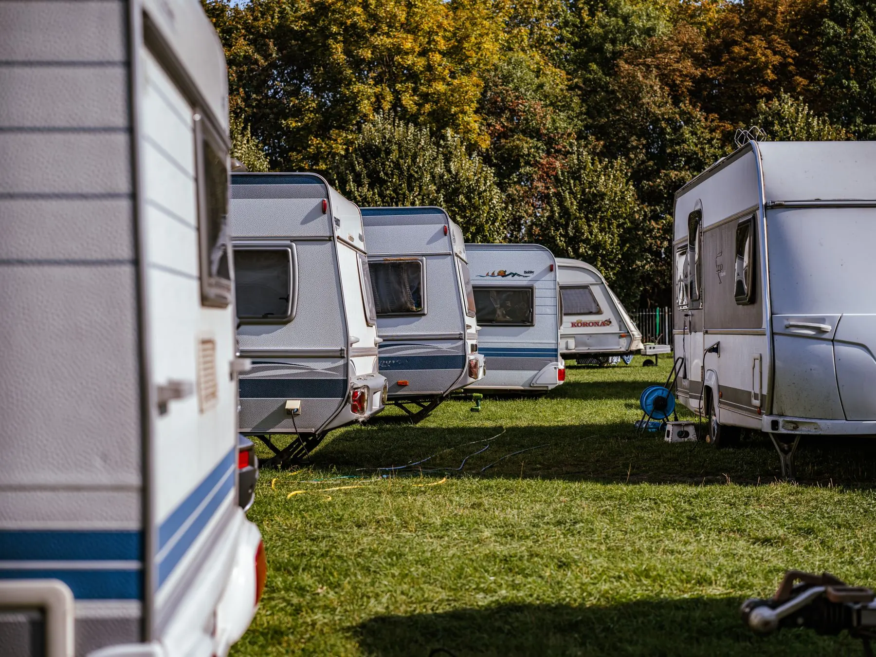 Camping avec plusieurs caravanes et camping-cars stationnés parmi les arbres