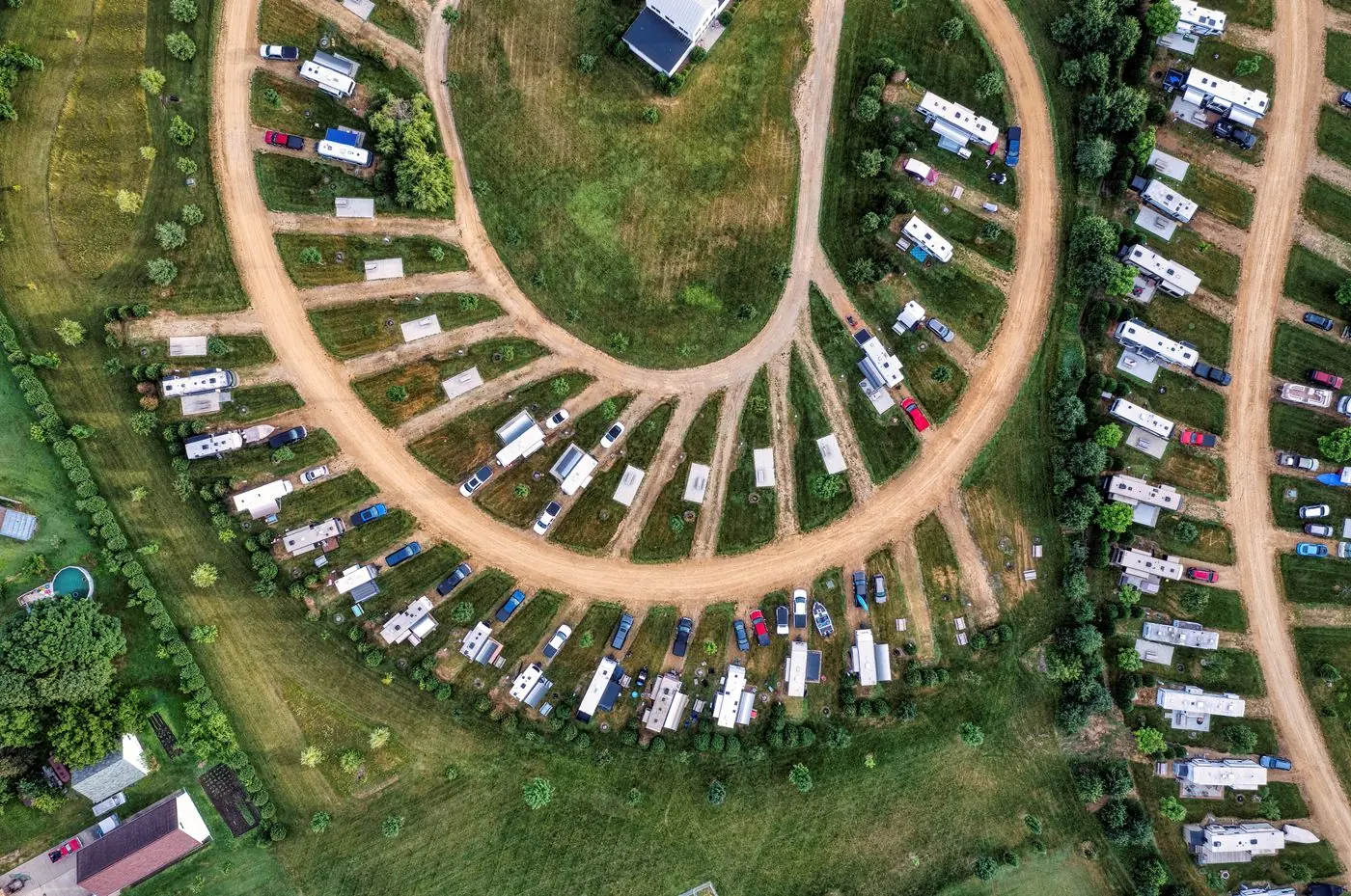 Parc de camping avec emplacements disposés en demi-cercle dans un cadre verdoyant